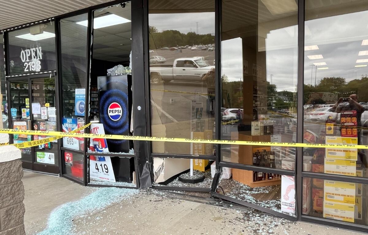 The front of the ABC Store and Vape Shop after a car drove into it. Glass on the ground and broken windows.