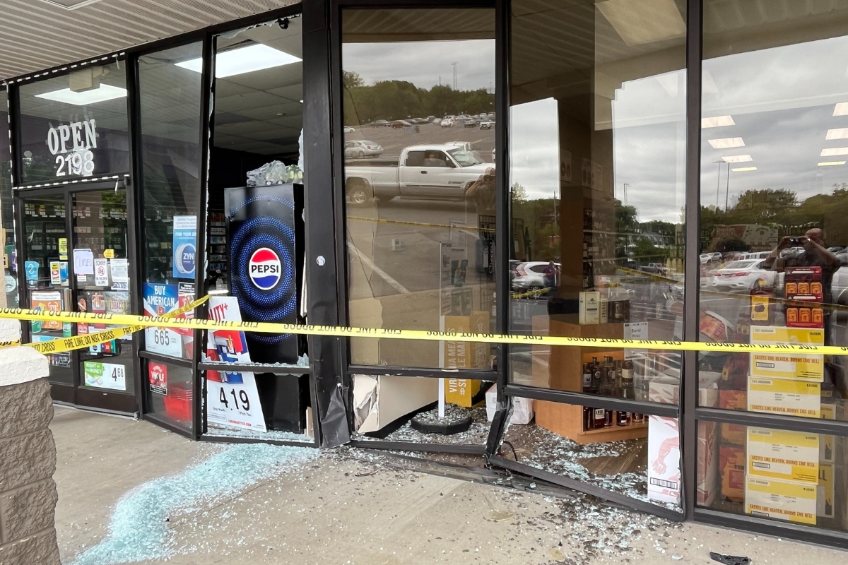 The front of the ABC Store and Vape Shop after a car drove into it. Glass on the ground and broken windows.