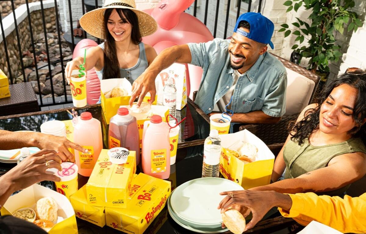 A group of people at a table with Bojangles food and drinks.