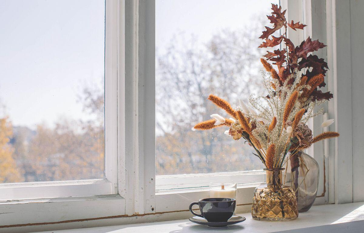 Cup of coffee in front of window with a fall bouquet