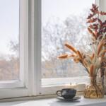 Cup of coffee in front of window with a fall bouquet
