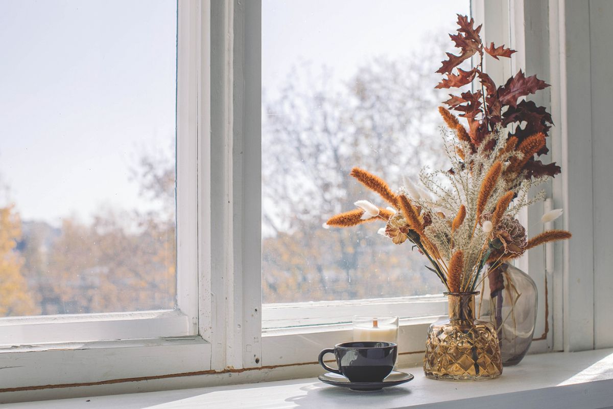 Cup of coffee in front of window with a fall bouquet