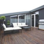 Outside deck with couch and chair and a grill.