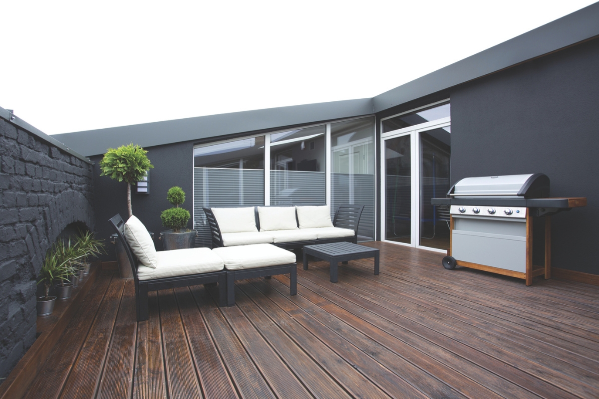 Outside deck with couch and chair and a grill.
