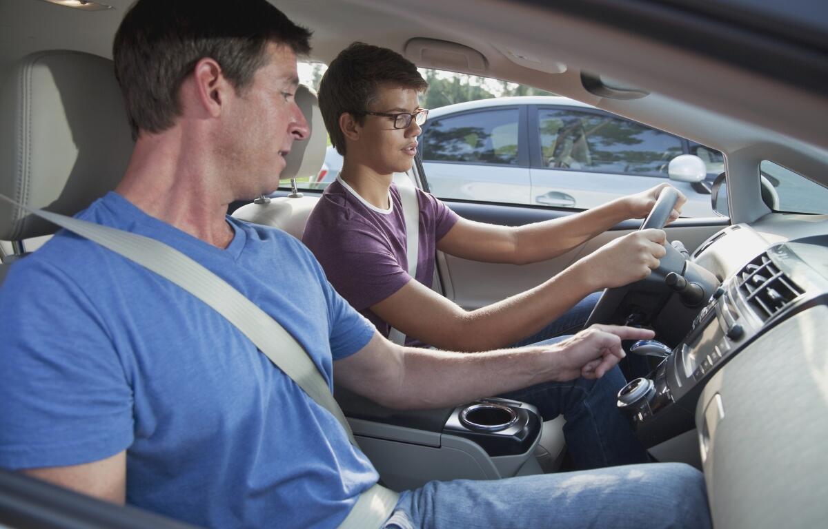 A man showing a teenager how to drive.