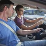 A man showing a teenager how to drive.