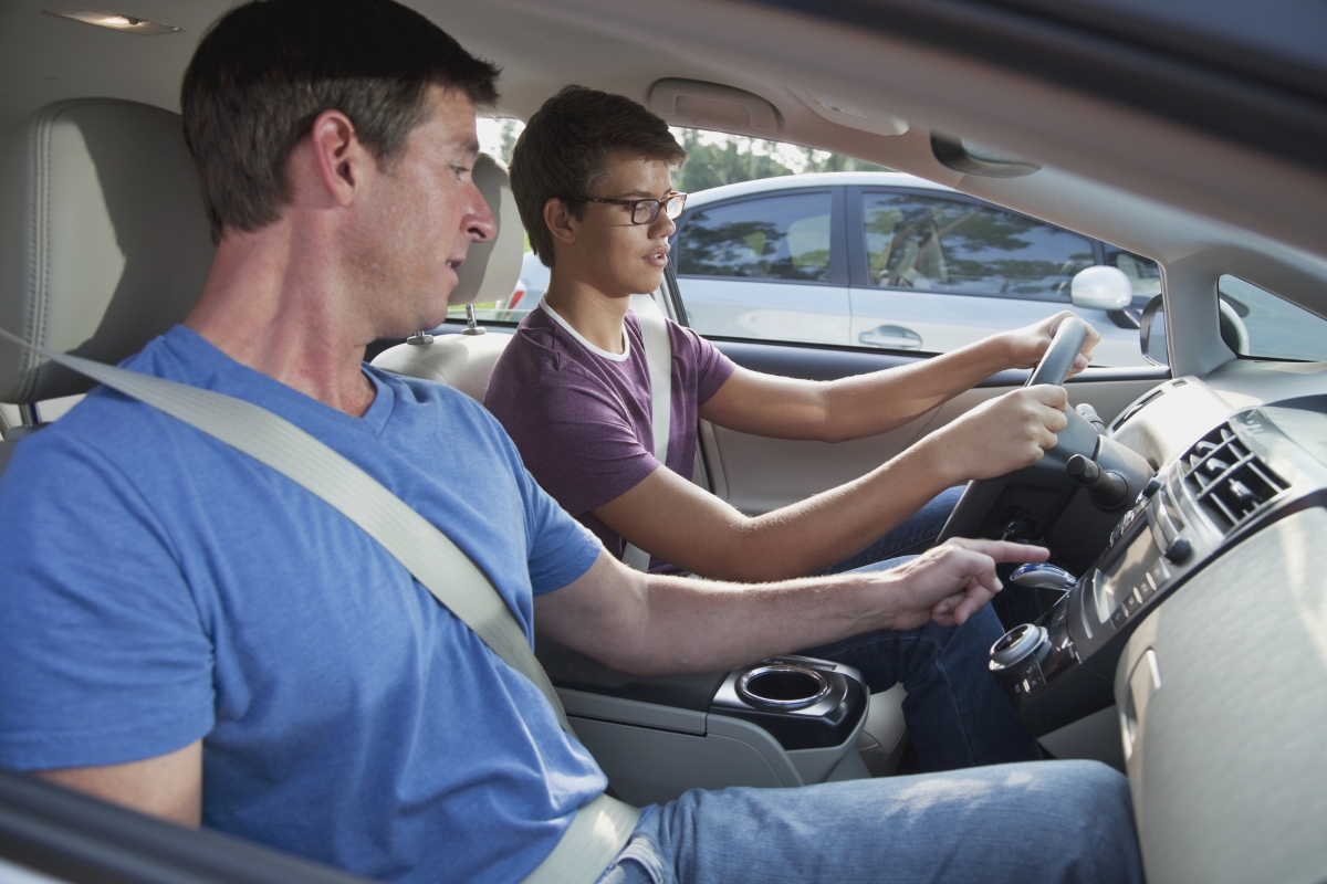 A man showing a teenager how to drive.