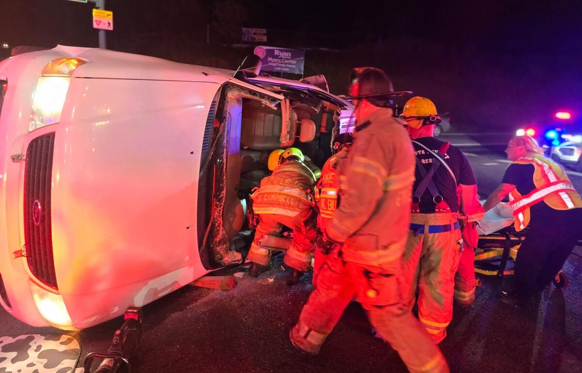 Firefighters rescuing the driver of a car flipped on its side.