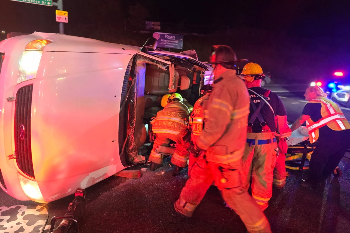 Firefighters rescuing the driver of a car flipped on its side.