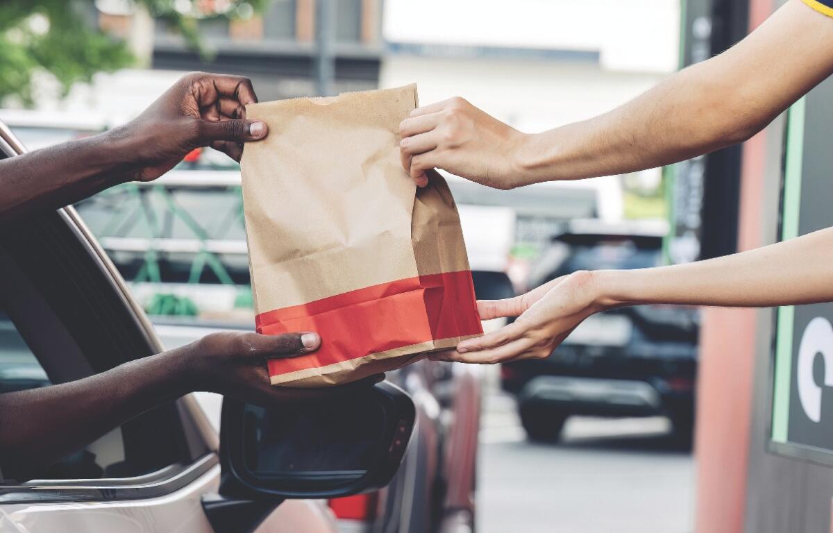 A fast food bag being handed to someone in a car.