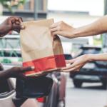 A fast food bag being handed to someone in a car.