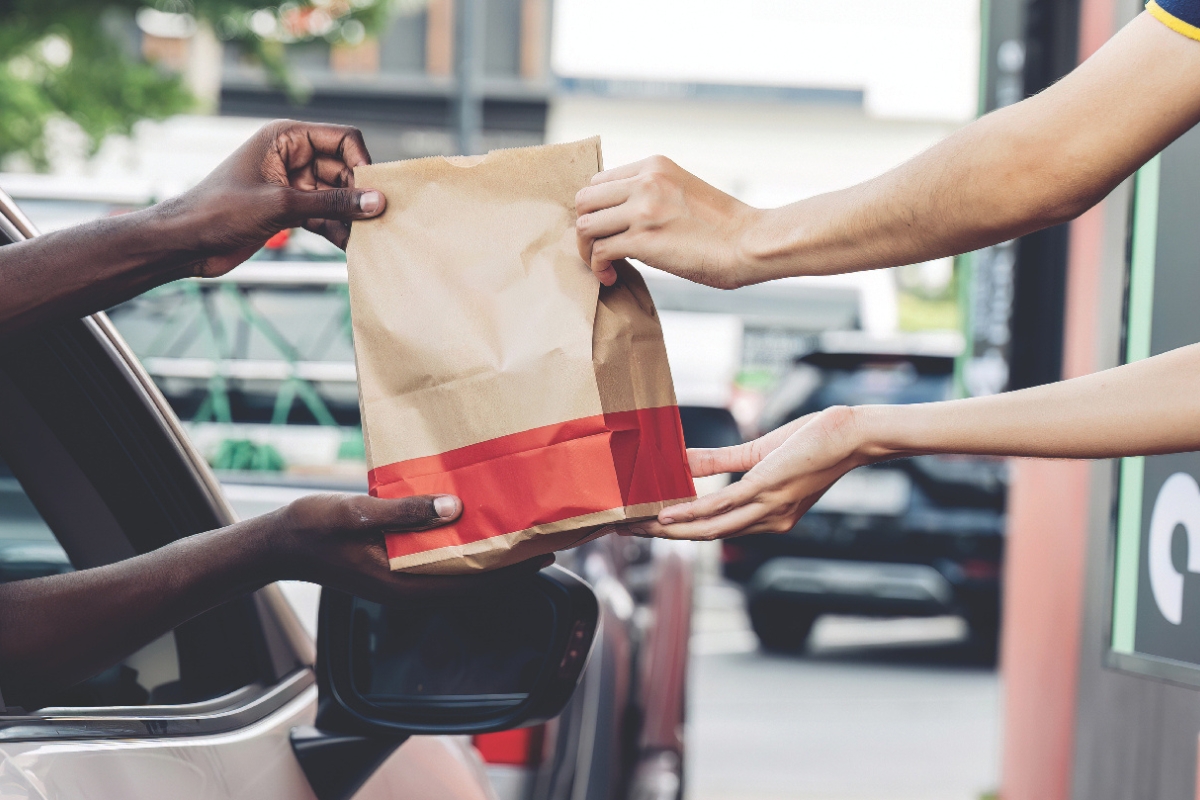 A fast food bag being handed to someone in a car.