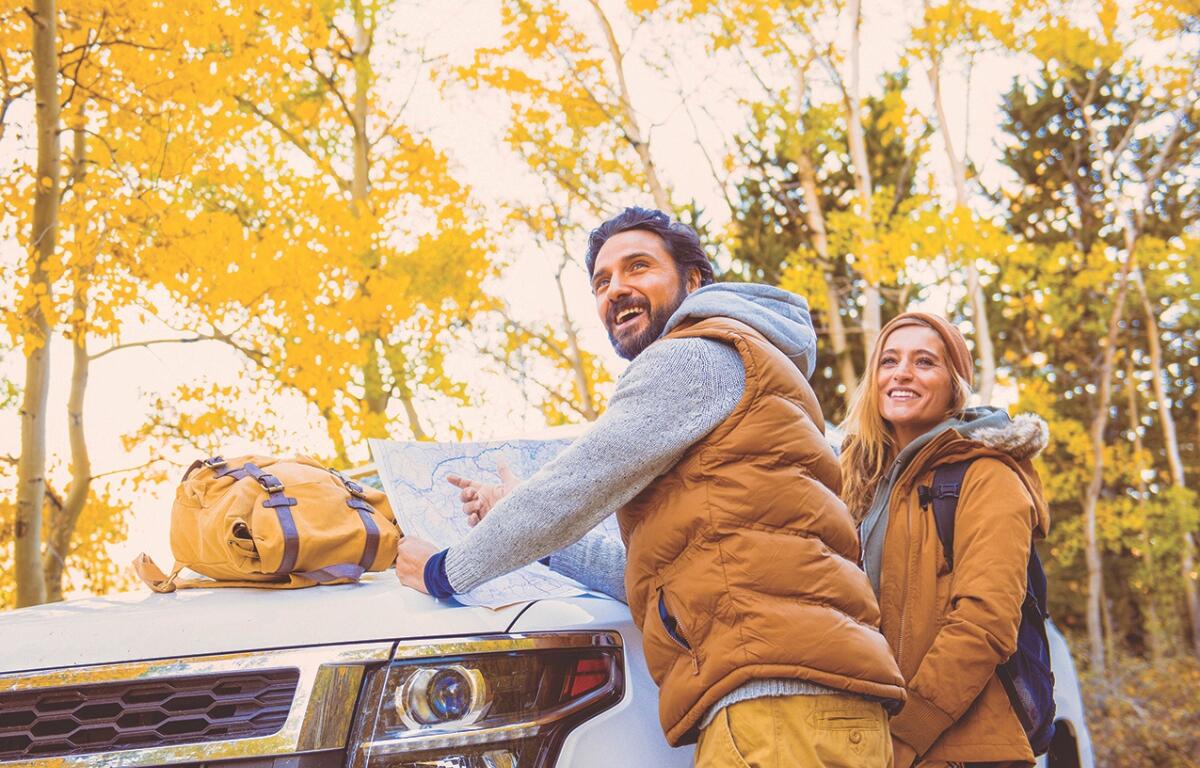 A couple outside in fall foliage looking at a map.
