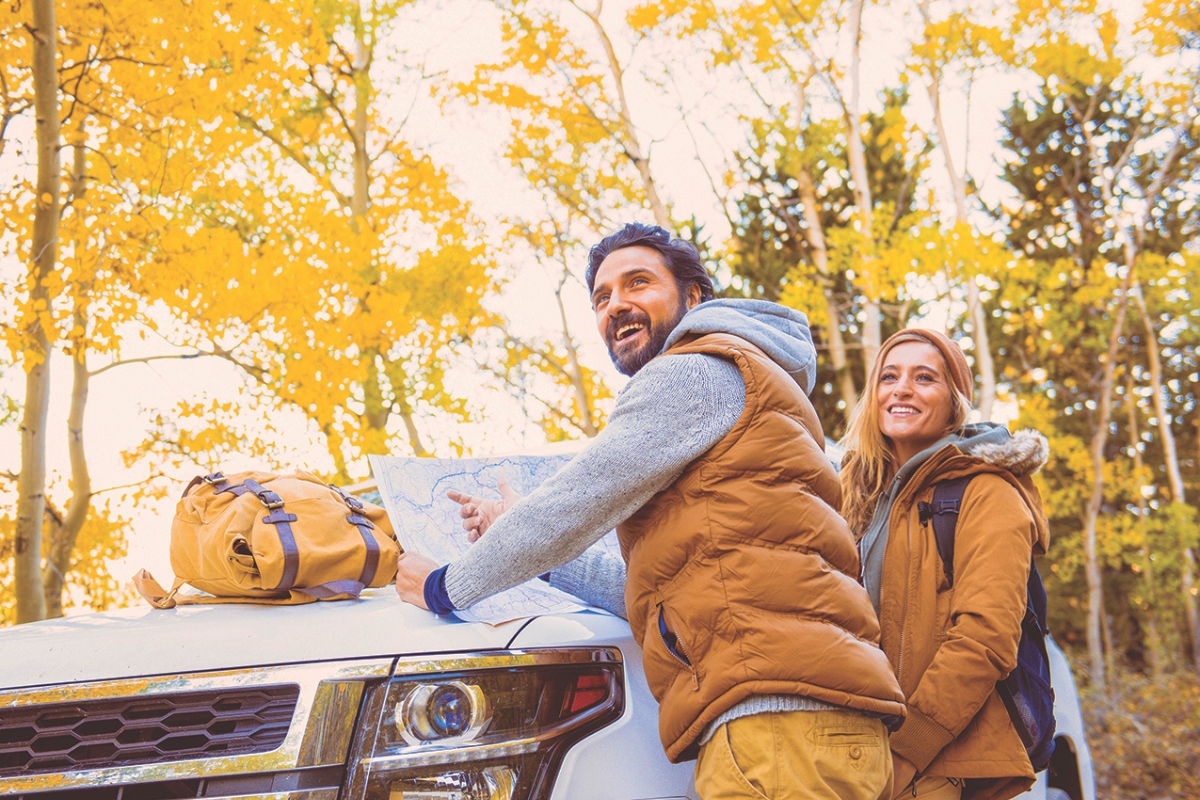 A couple outside in fall foliage looking at a map.
