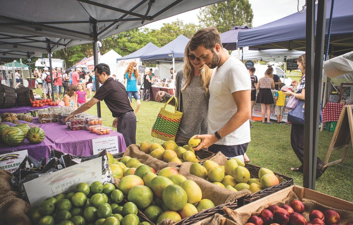 People browse produce at a farmers market.