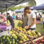 People browse produce at a farmers market.