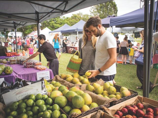People browse produce at a farmers market.