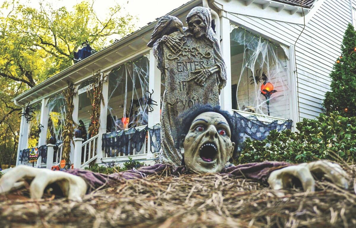 Lots of halloween decorations on a porch and yard.