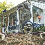 Lots of halloween decorations on a porch and yard.