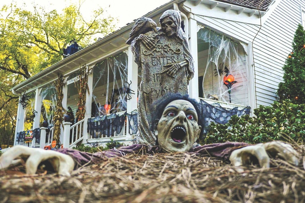 Lots of halloween decorations on a porch and yard.