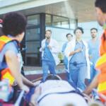 EMS personnel roll a gurney up to a hospital with doctors and nurses waiting.