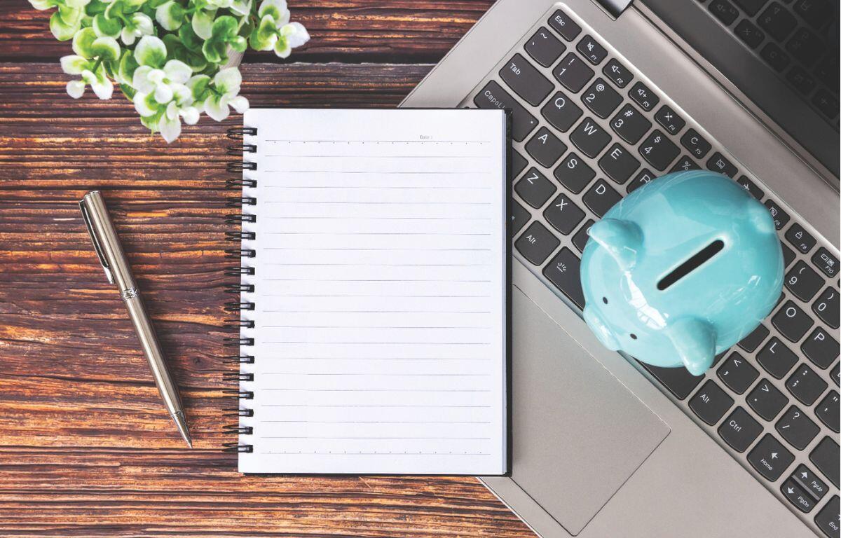 Notebook and piggy bank on top of a laptop