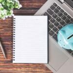 Notebook and piggy bank on top of a laptop