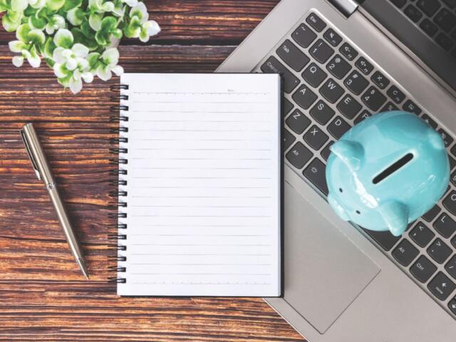 Notebook and piggy bank on top of a laptop
