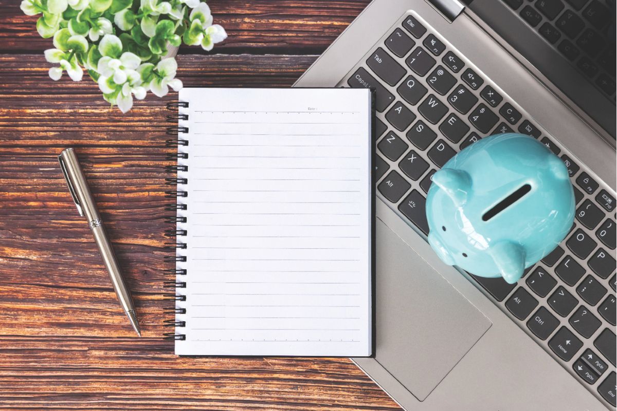 Notebook and piggy bank on top of a laptop