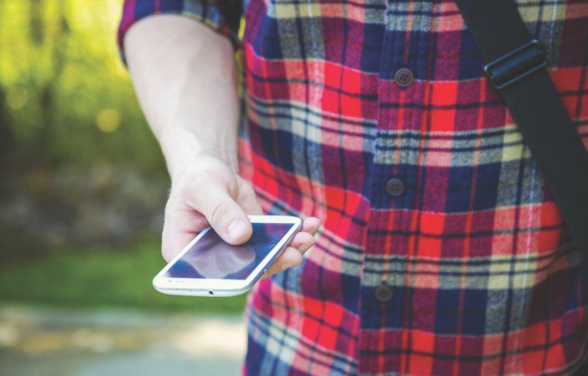 Man wearing a flannel and holding a phone