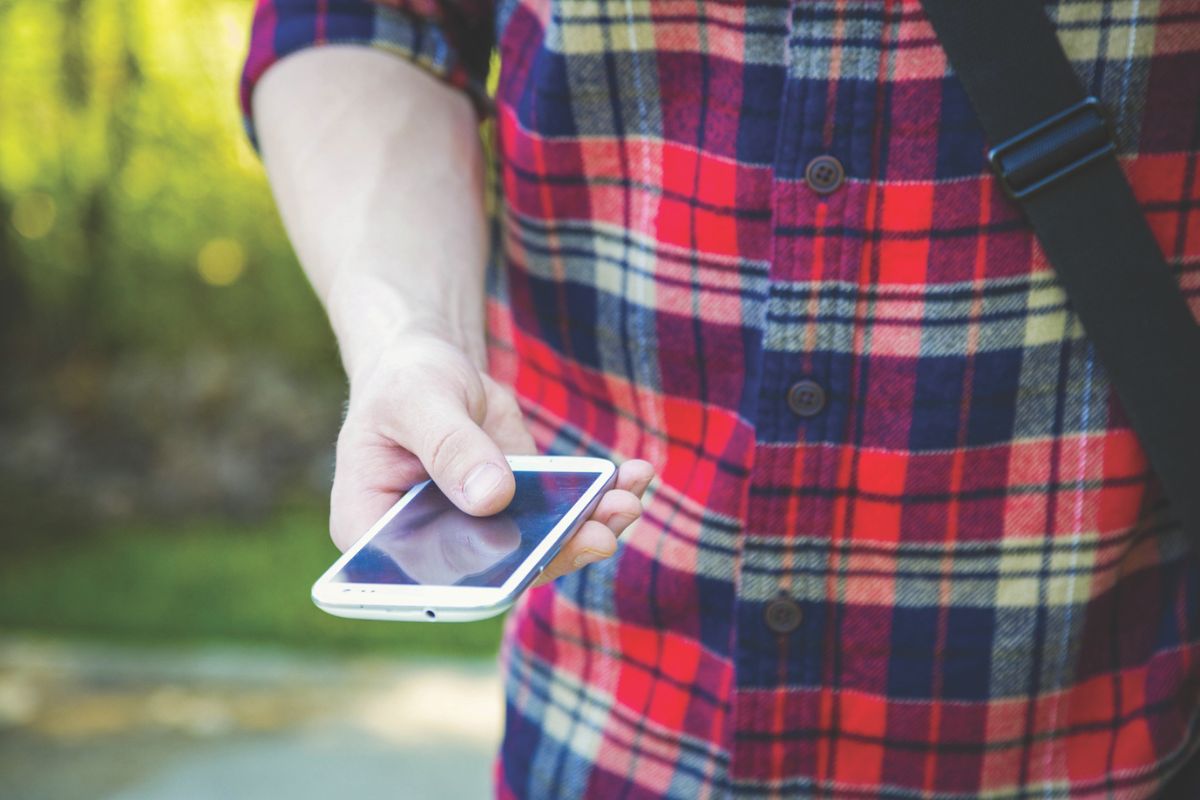 Man wearing a flannel and holding a phone