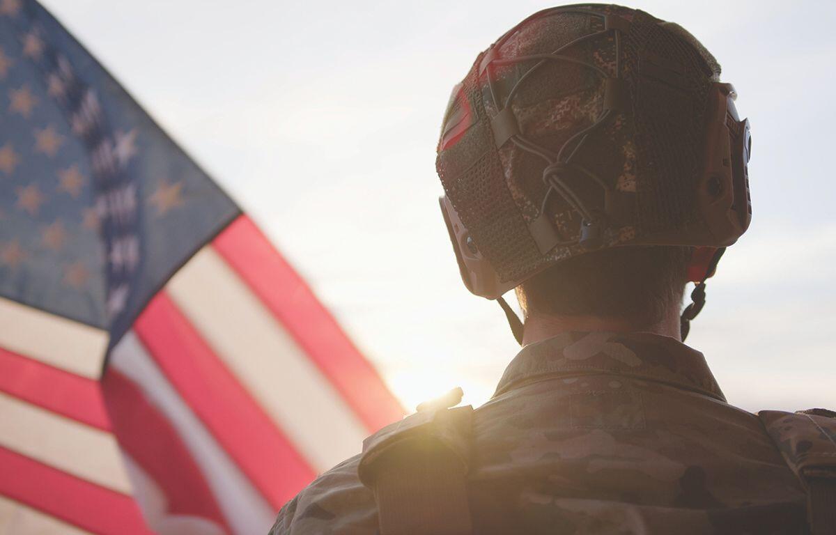 Soldier standing beside the American Flag