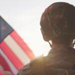 Soldier standing beside the American Flag