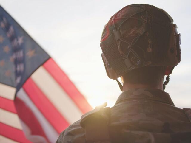 Soldier standing beside the American Flag