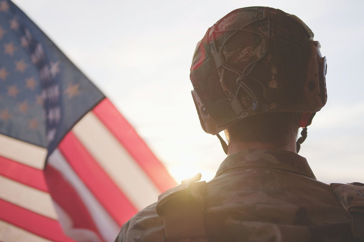 Soldier standing beside the American Flag