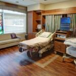 A setup for a family birthplace at Sentara with a bed, couch, medical equipment and a window.