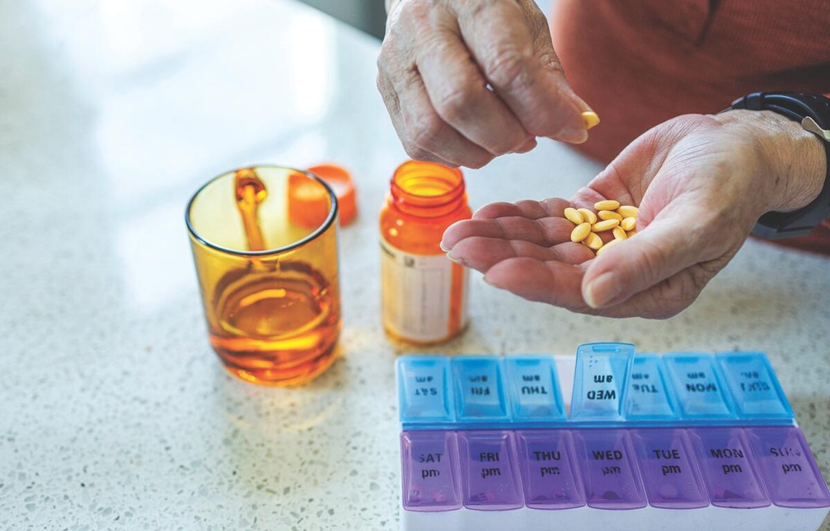A person putting pills into a weekly pill sorter.