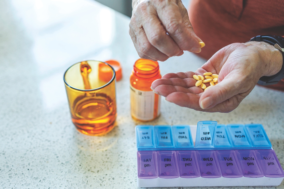 A person putting pills into a weekly pill sorter.