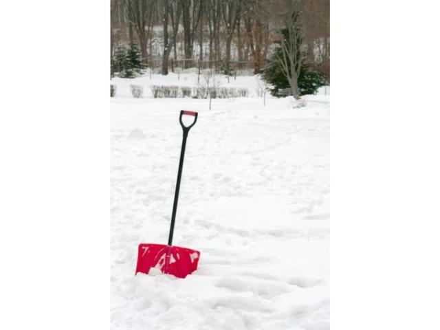 Red plastic shovel with black handle stuck in fluffy white snow.