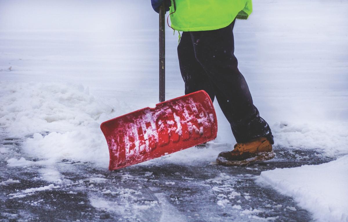 A person shoveling snow on pavement.