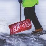 A person shoveling snow on pavement.
