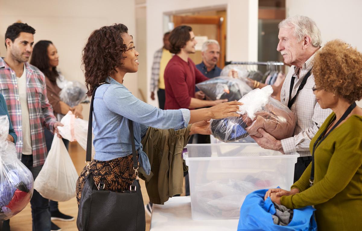 People Donating Clothing To Charity Collection In Community Center