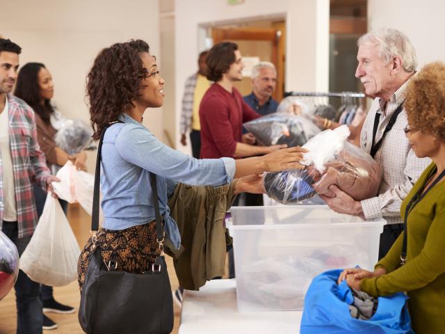 People Donating Clothing To Charity Collection In Community Center