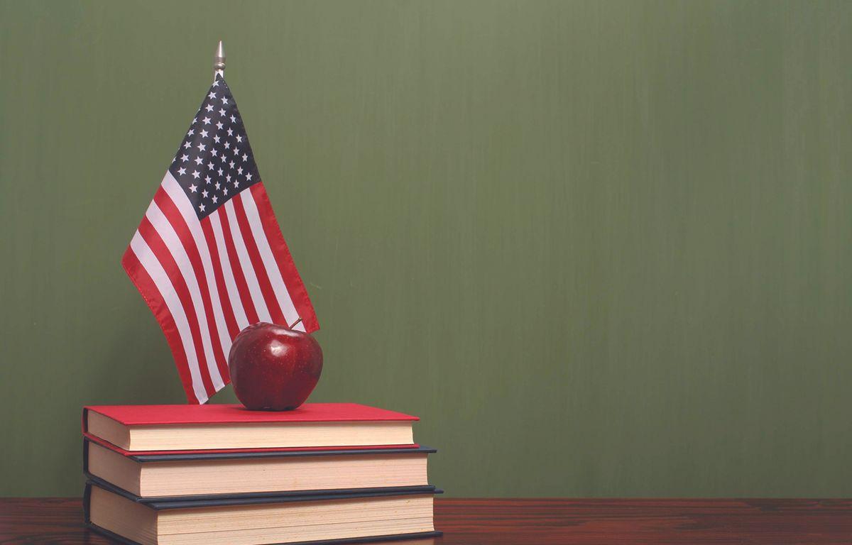 An apple on top of books with an American flag on a desk