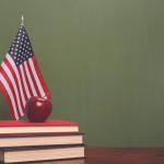 An apple on top of books with an American flag on a desk