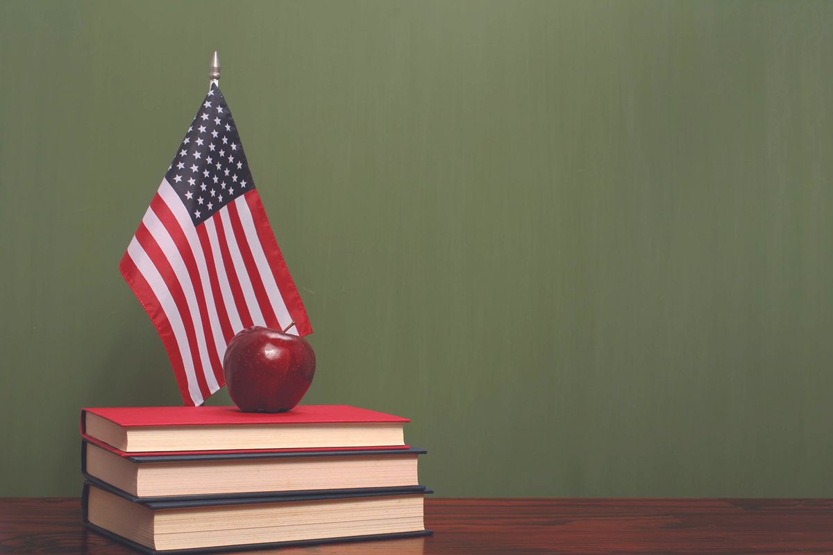 An apple on top of books with an American flag on a desk
