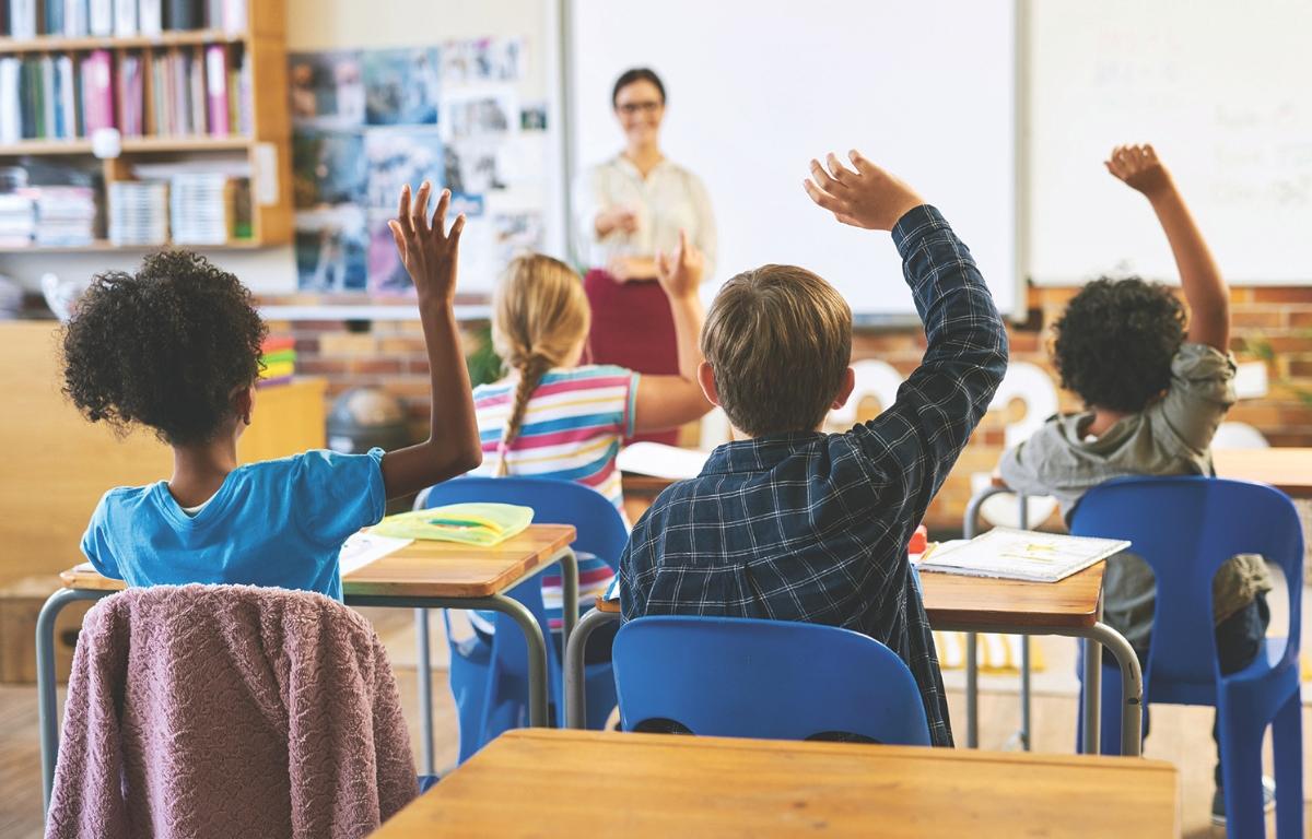 Students raise their hands in a classroom.