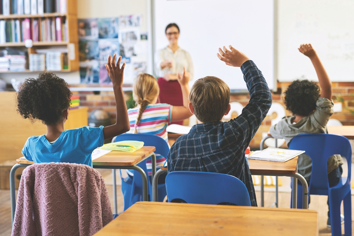 Students raise their hands in a classroom.