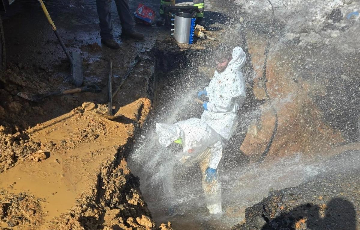 Public Works crews are repairing a break while water sprays them and freezes over the site.