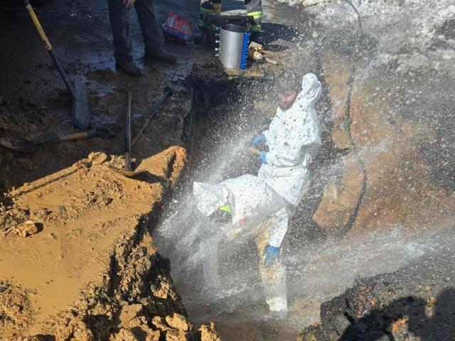 Public Works crews are repairing a break while water sprays them and freezes over the site.